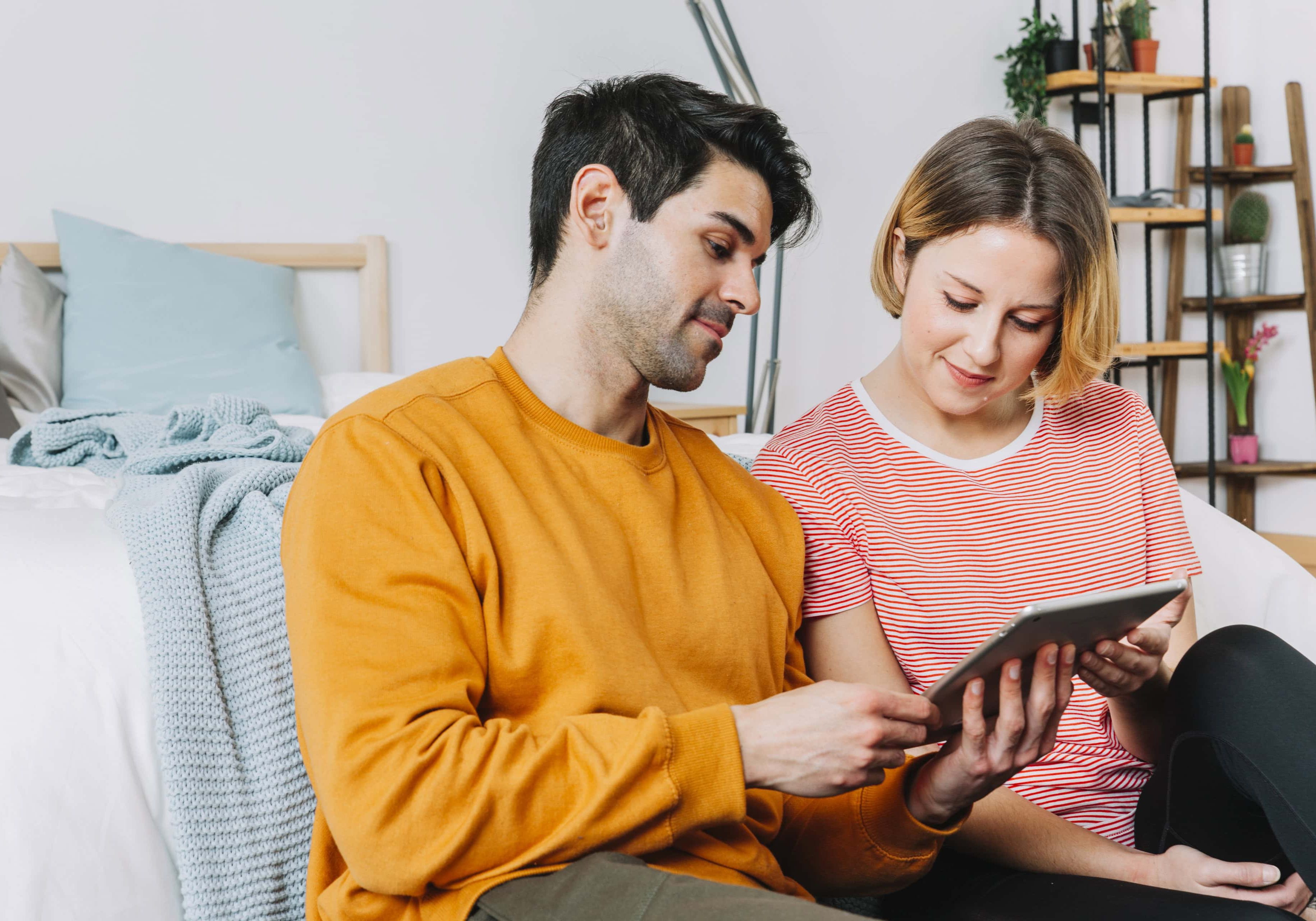 beautiful-couple-using-tablet-near-bed